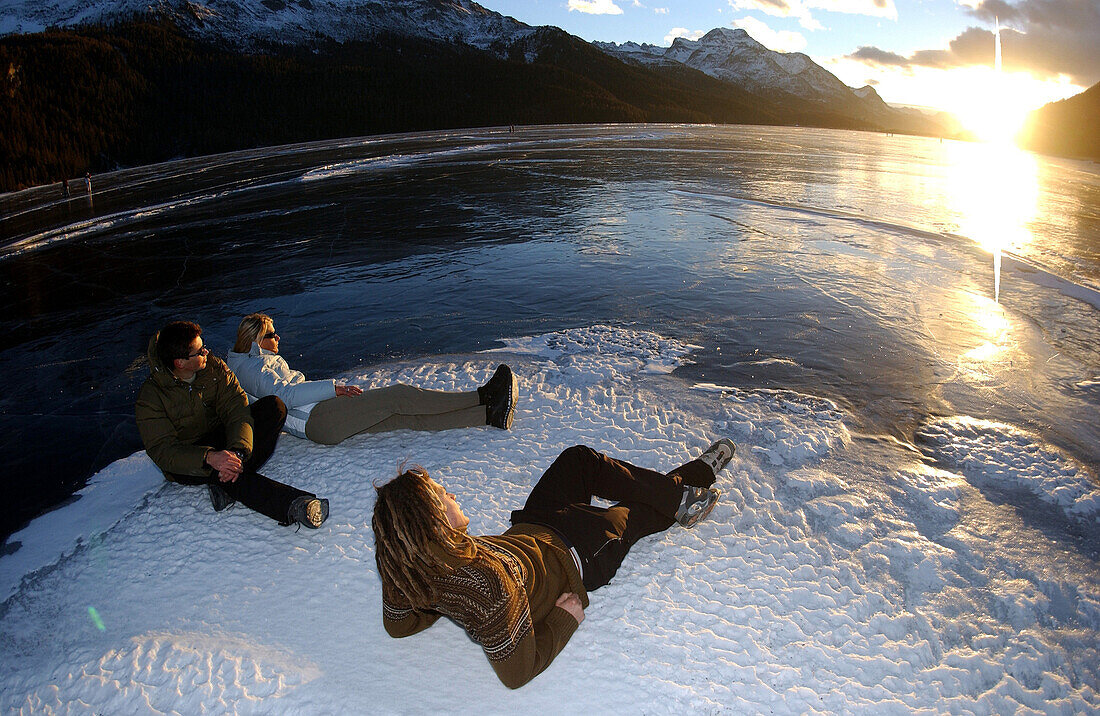 Drei Personen betrachten den Sonnenuntergang, Silvaplanasee, Graubünden, Schweiz
