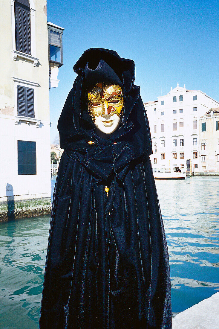 Masked person in disguise in front of a canal, Venice, Italy, Europe
