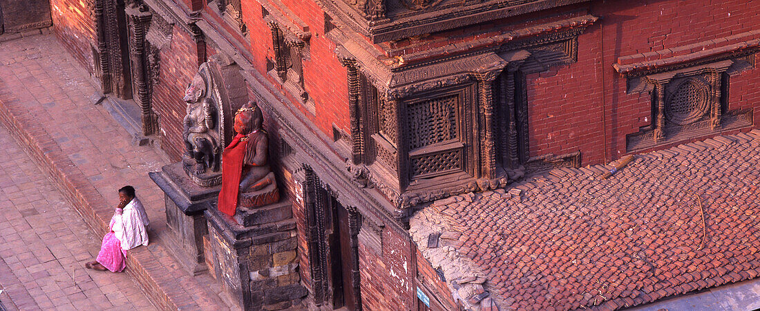 Woman sitting in front of a temple on a step, Durbar Square, Patan, Nepal, Asia