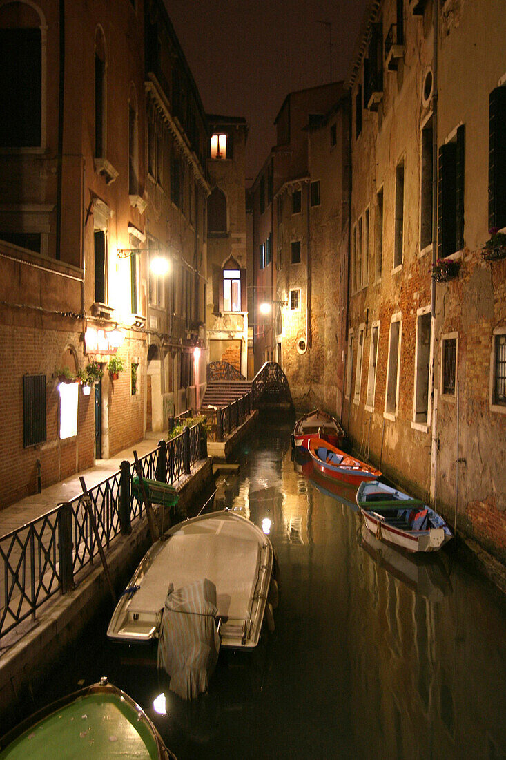 Beleuchteter Kanal mit Booten bei Nacht in Venedig, Italien
