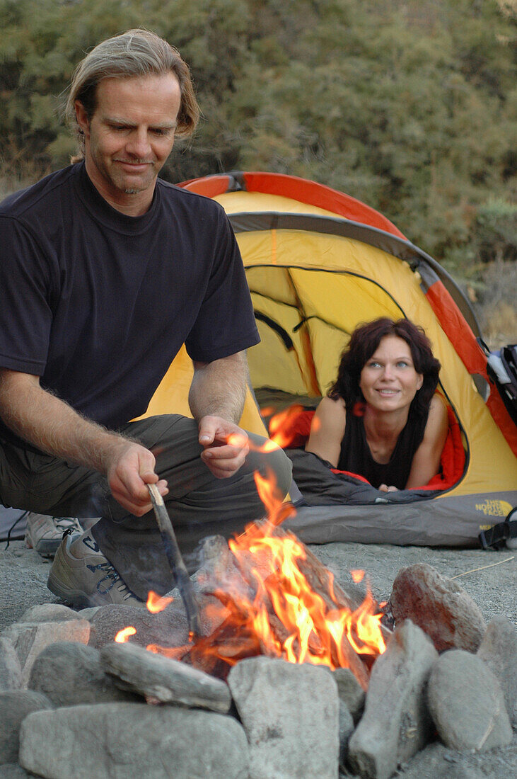 Paar beim Zelten, Mann kocht am Lagerfeuer, Camping, Andalusien, Spanien