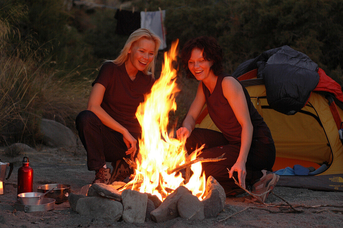 Two women sat around the campfire, Camping, Andalusia, Spain