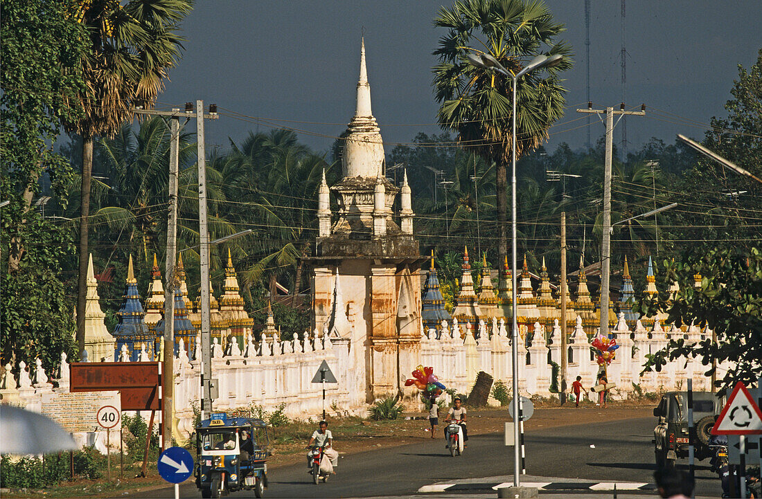 Menschen auf einer Strasse vor Tempelanlage Wat Pha Baat, Pakse, Südlaos, Laos