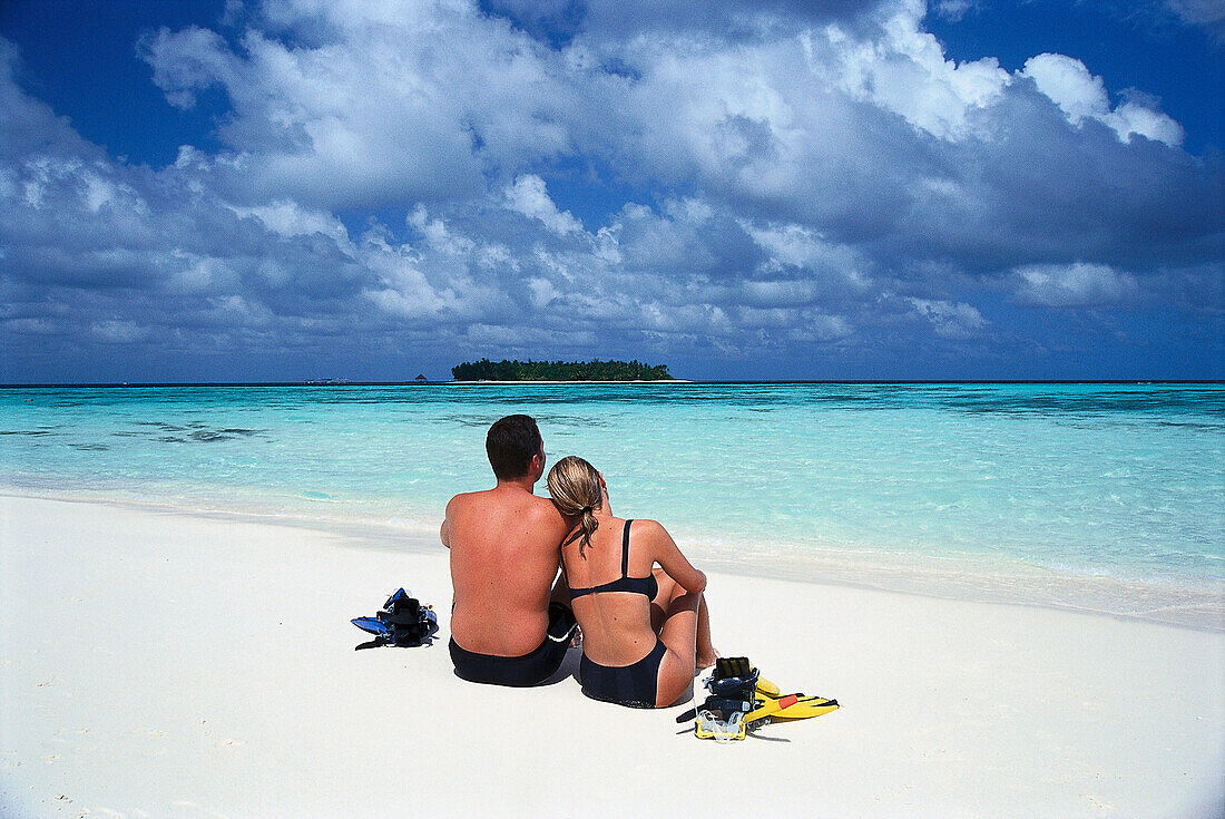 Junges Paar sitzt am Strand, Hotel Banyan Tree Spa, Vabbinfaru, Malediven, Indischer Ozean