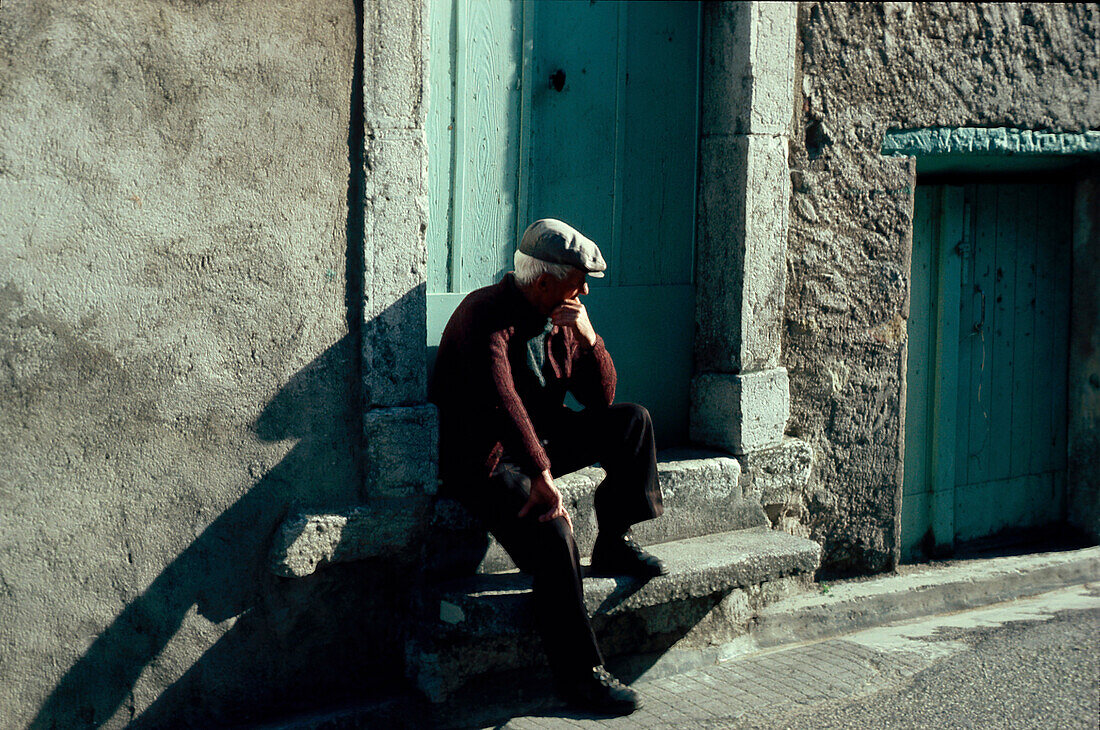 Alter Mann sitzt auf Treppenstufen in der Provence, Frankreich