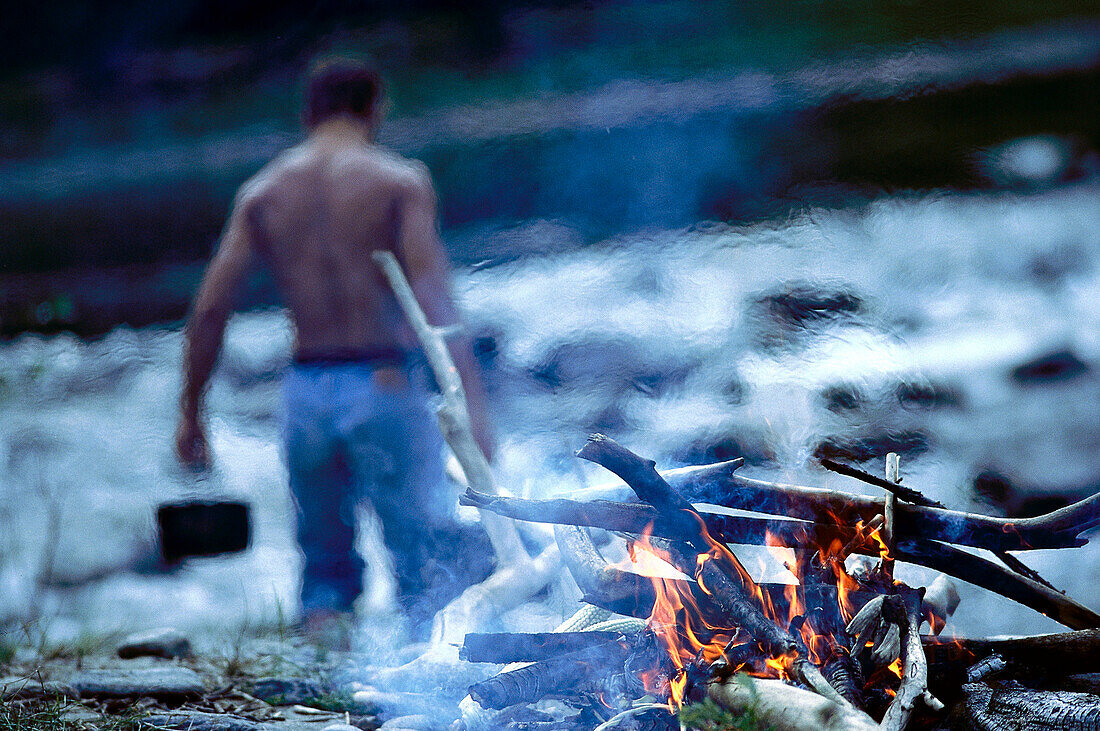 Lagerfeuer, Mann mit freiem Oberkörper im Hintergrund, Oberbayern, Deutschland