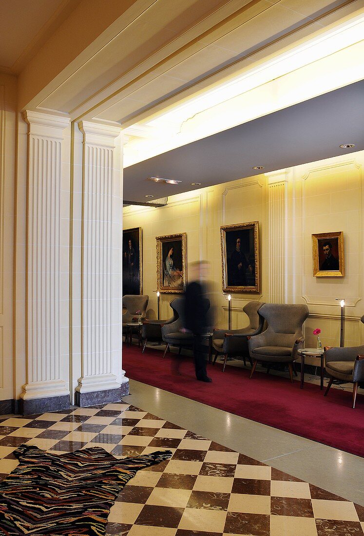 A reception area with a tiled, chessboard floor and a red carpet runner in the hallway