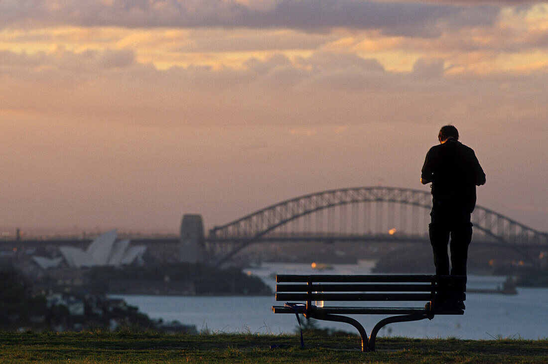 Photographing the Harbour Bridge, Australien, Sydney Harbour Bridge, Abendlicht, Tourist taking a photo of the Harbour Bridge and Opera House at sunset, from park bench