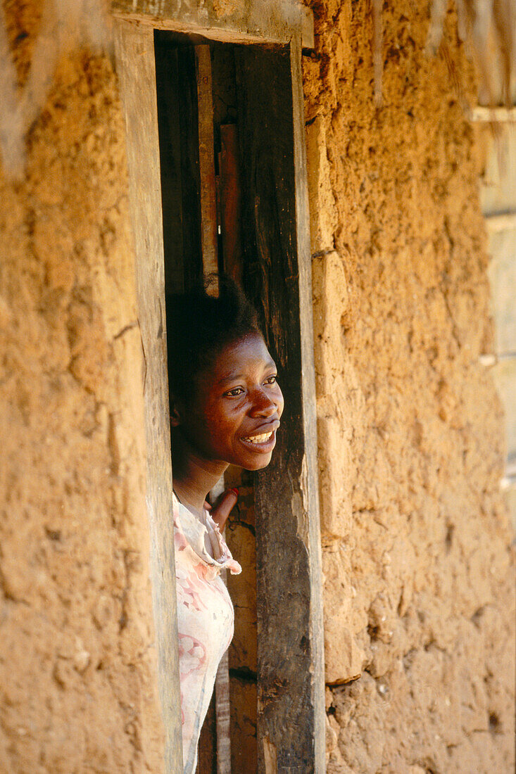 Afrikanische Frau schaut freundlich aus Lehmhütte, Sansibar, Tansania, Afrika
