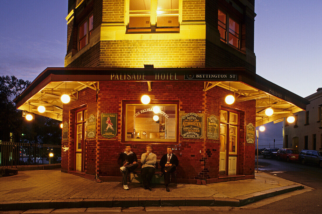 Palisade Hotel, pub in the Rocks, Sydney, Australien, NSW, Three men sitting in front of pub drinking beer after work in the historic quarter called The Rocks, Vor der beleuchtete Kneipe sitzen drei Männer und trinken Bier am Feierabend