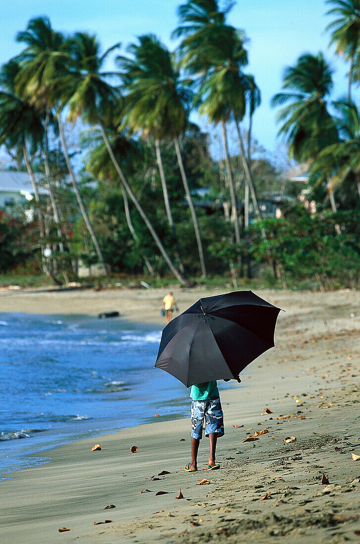 Junge mit Sonnenschirm am Strand, Tobago West Indies, Karibik