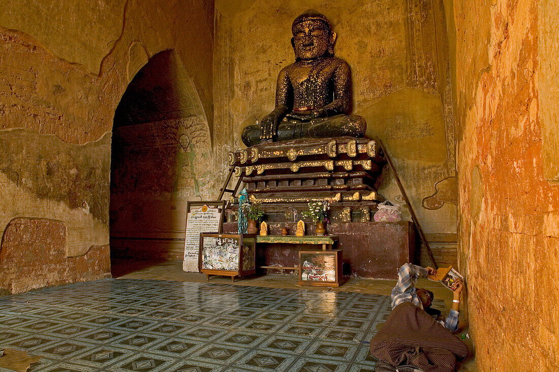 Buddha statue, Sulamani Temple, Buddhafigur Sulamani mit Blattgold beklebt, Waechter liest auf dem Boden, Bagan Buddha statue, black with gold leaf, watchman lies reading on the floor, Pagan