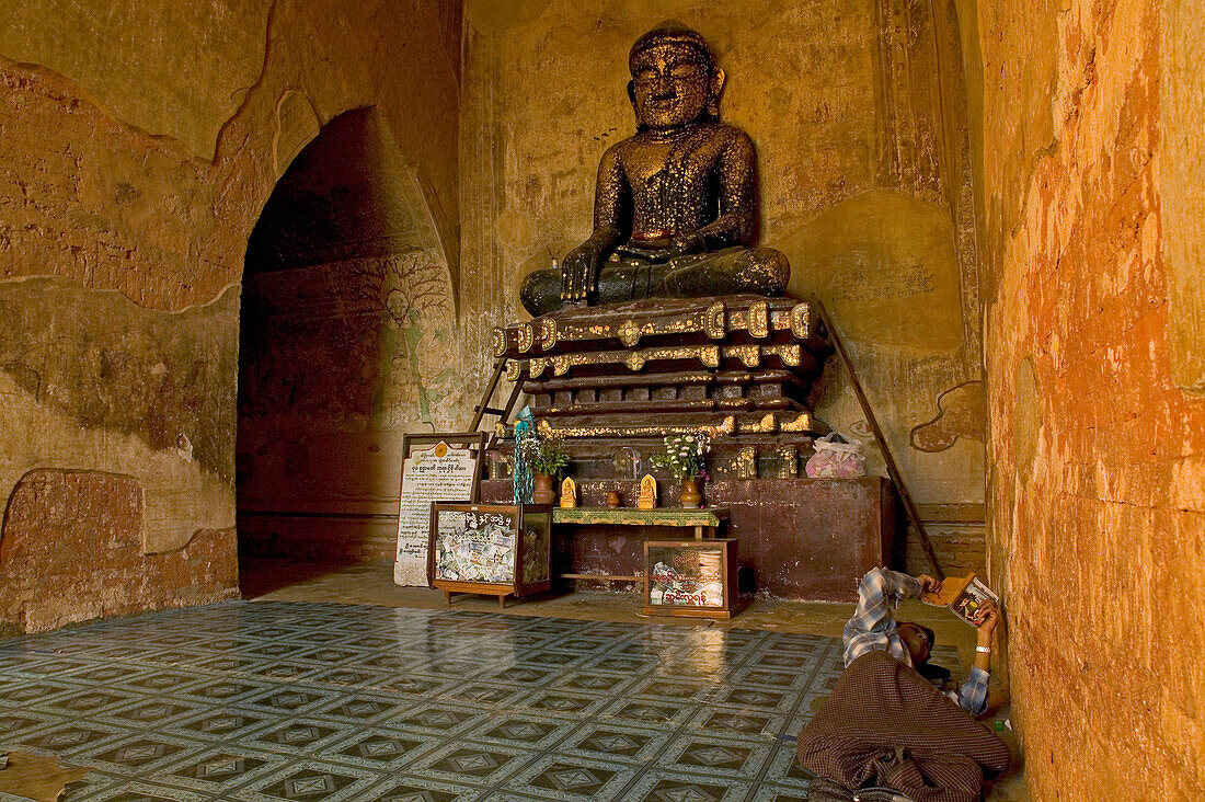 Sulamani Temple, Buddha statue, watchman lies reading on the floor, Pagan, Myanmar