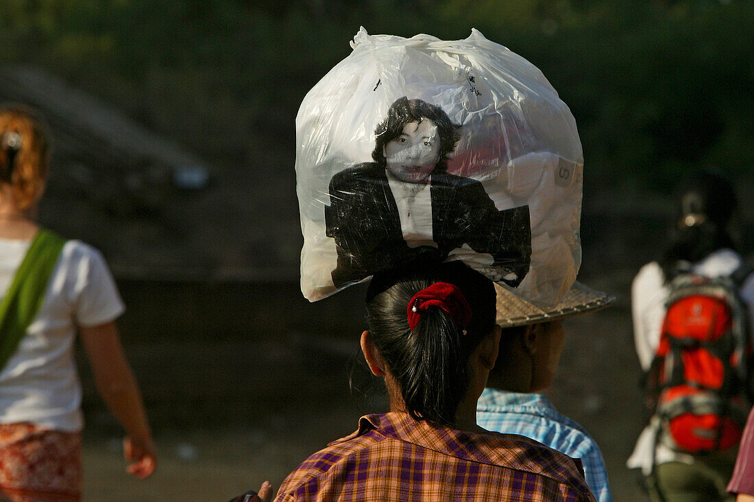 Women balancing plastic bag on head, Frau balanciert eine volle Plastikbeutel auf dem Kopf