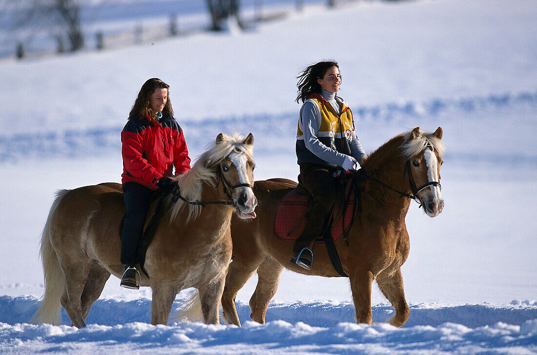 Zwei Frauen reiten auf Pferden durch den Schnee, Ramsau, Steiermark, Österreich, Europa