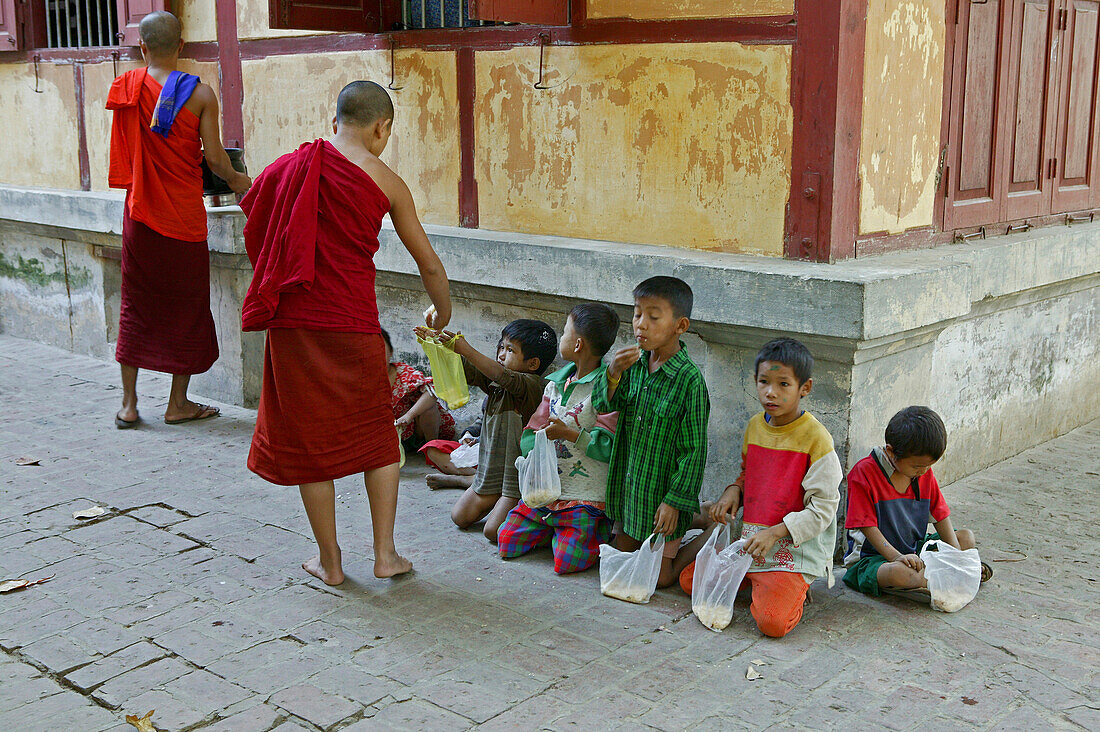 Mahagandaryone Monastery, Children line up for rice from monks in the monastery grounds, Essenausgabe fuer arme Kinder im Kloster, Amarapura bei Mandalay