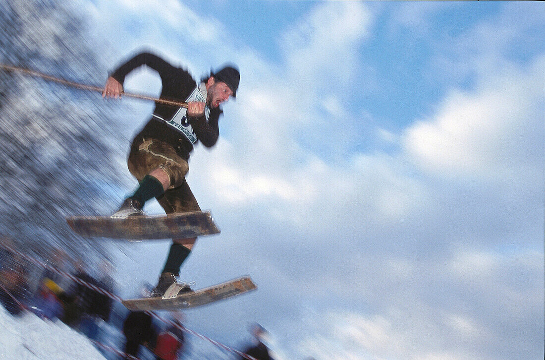 Man wearing traditional costume with wooden skis during a jump, Austria, Europe