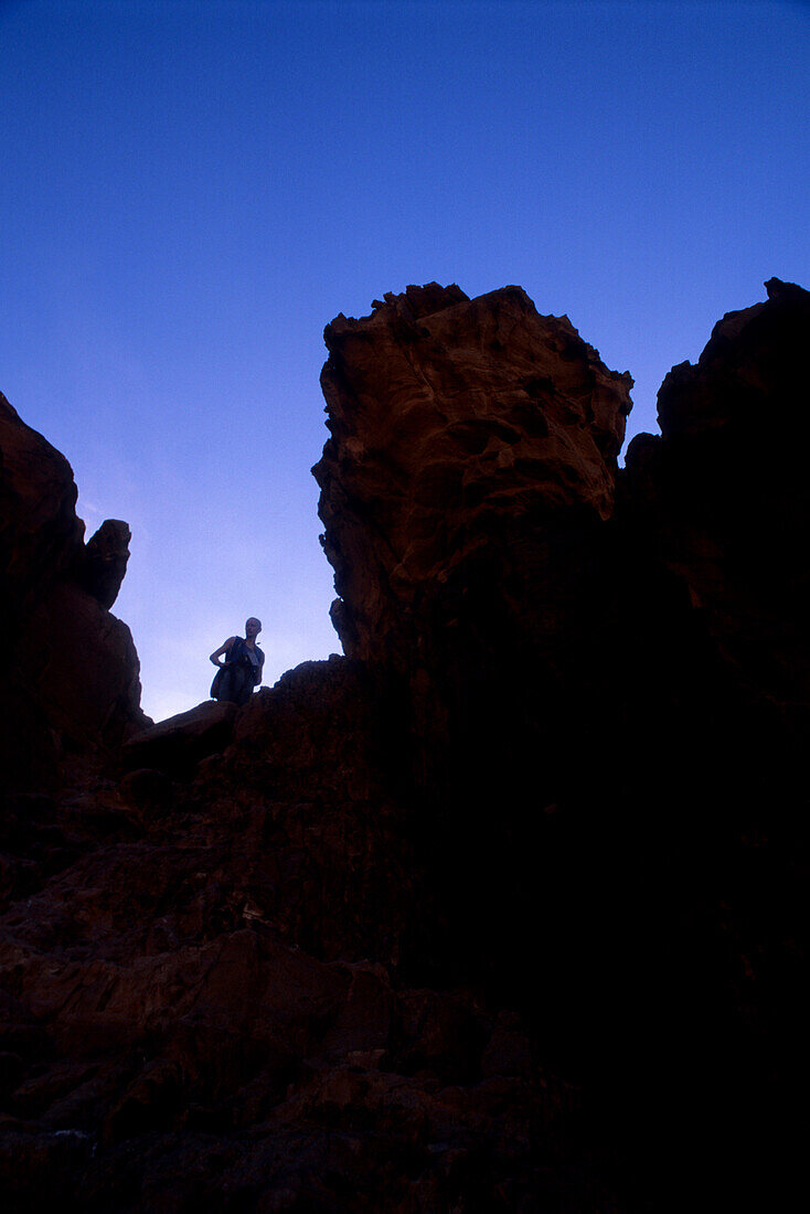 Mensch klettert auf einen Felsen, Rakabat, Wadi Rum, Jordanien