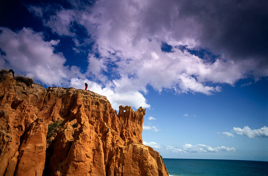 Golfer swinging on rugged terrain, Algarve, Portugal, low angle view