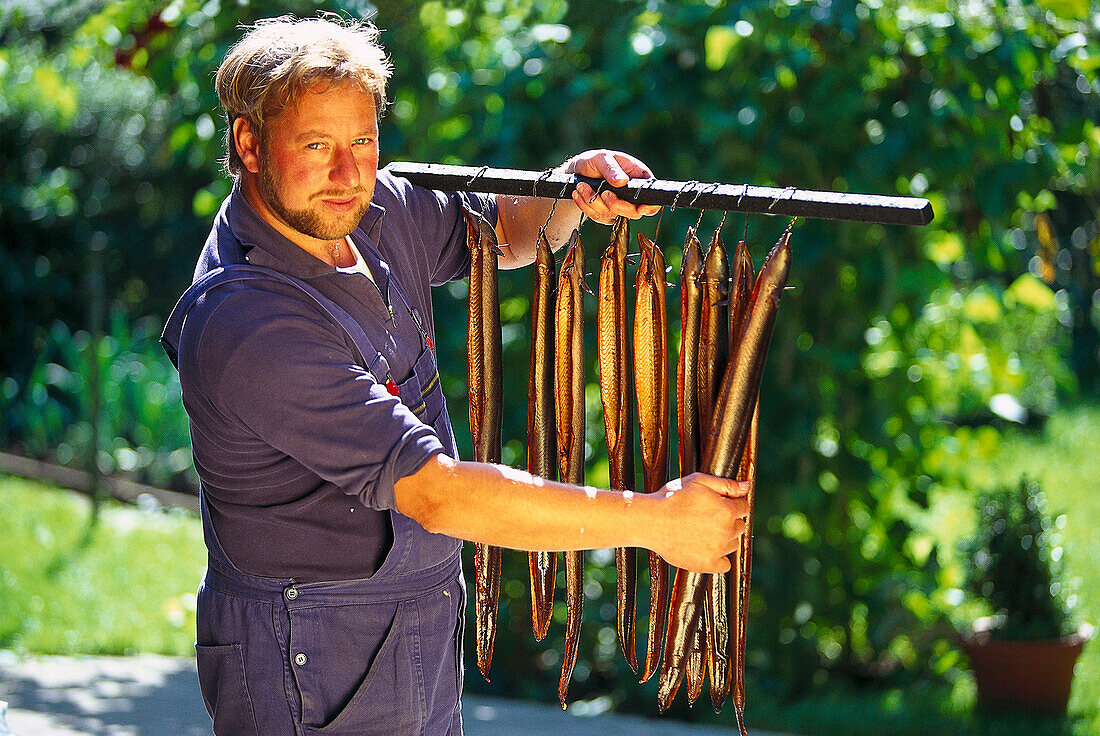 Fischer, Proud fisherman with cured eel, Chiemsee, Bavaria