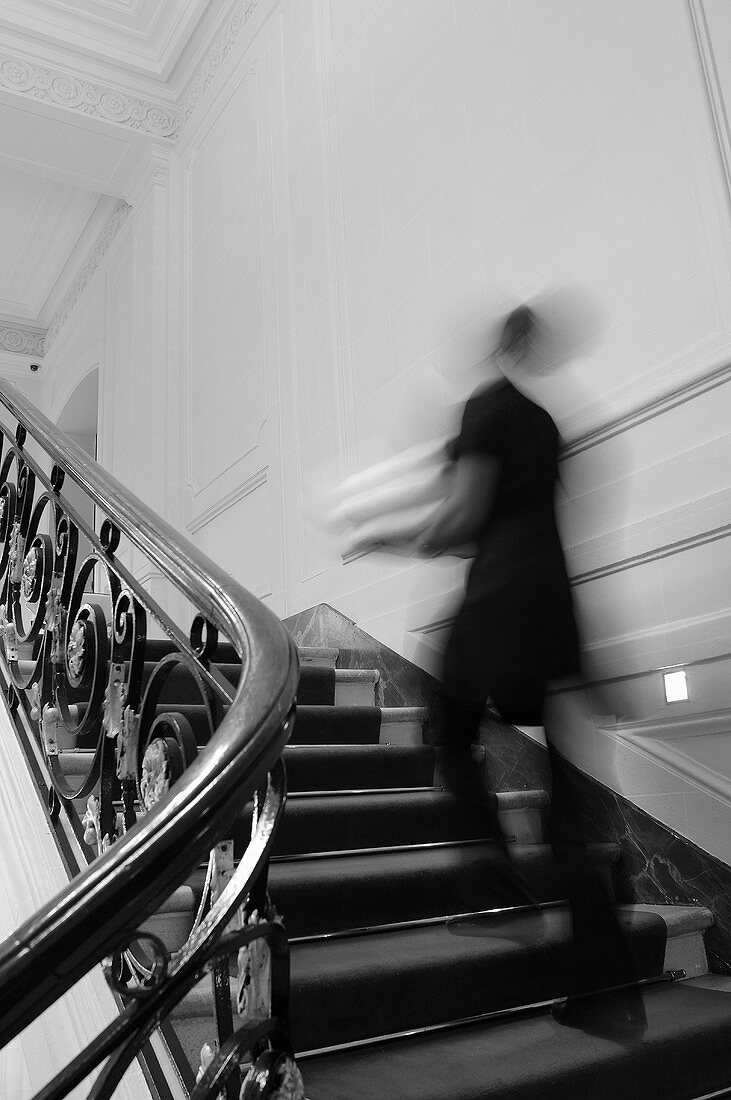 Person läuft, in einem eleganten Haus, die Treppe hinauf