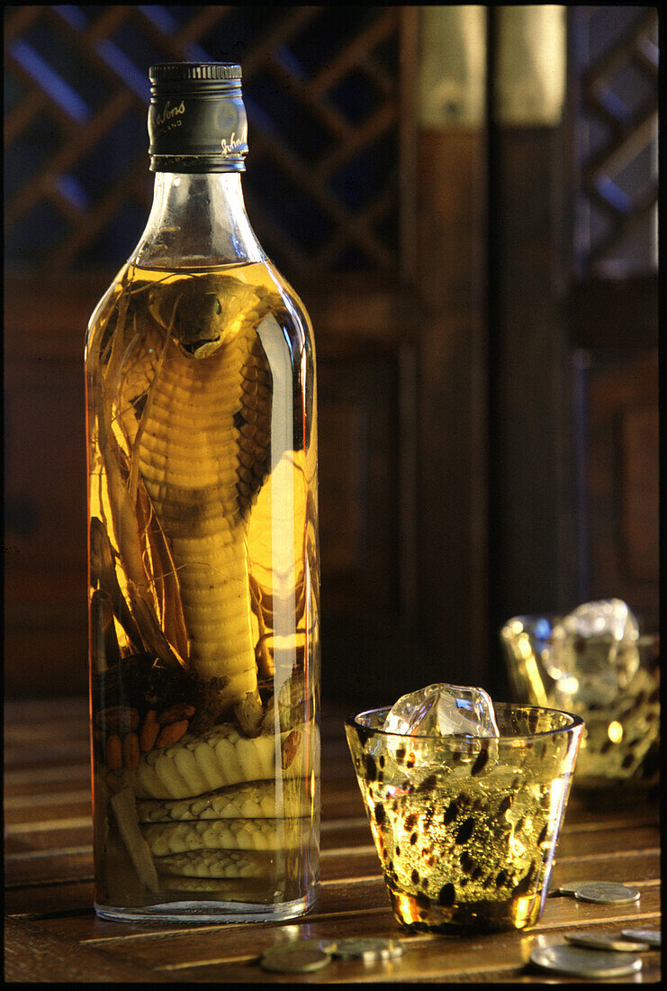 Bottle of spirits with pickled cobra and glass with ice cubes, Saigon, Vietnam, Asia