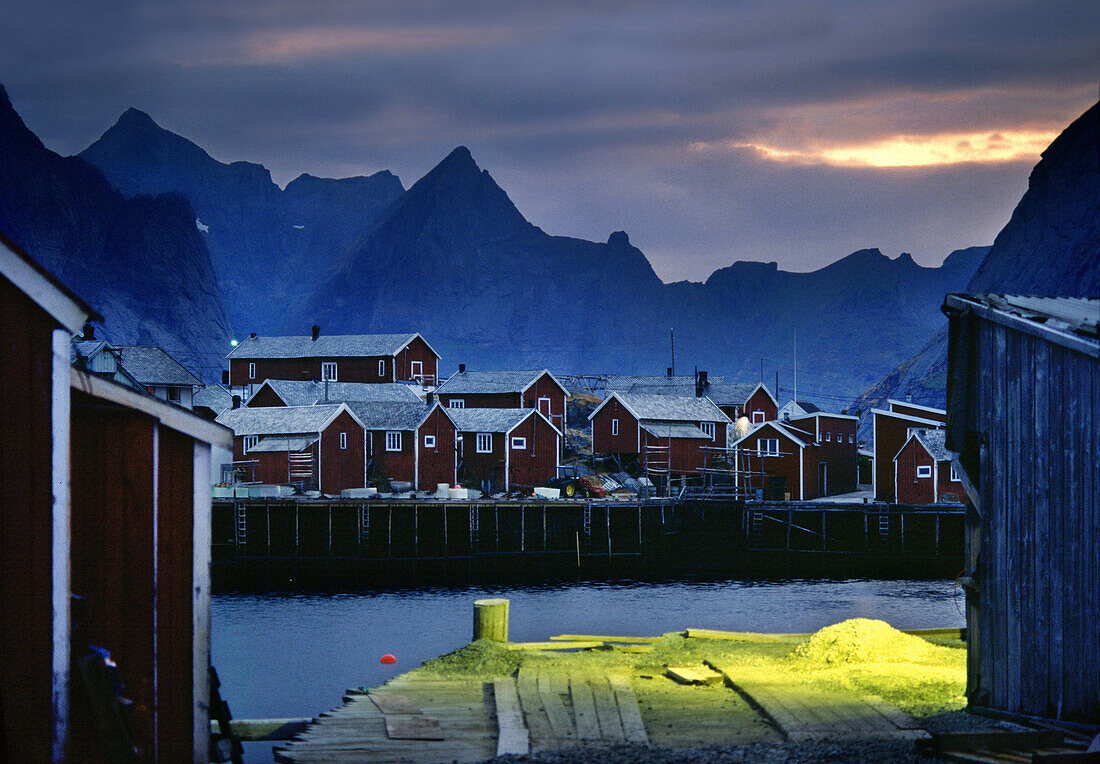 Rorbu Hütten in einem Fischerdorf unter Wolkenhimmel am Abend, Reine, Lofoten, Norwegen, Skandinavien, Europa
