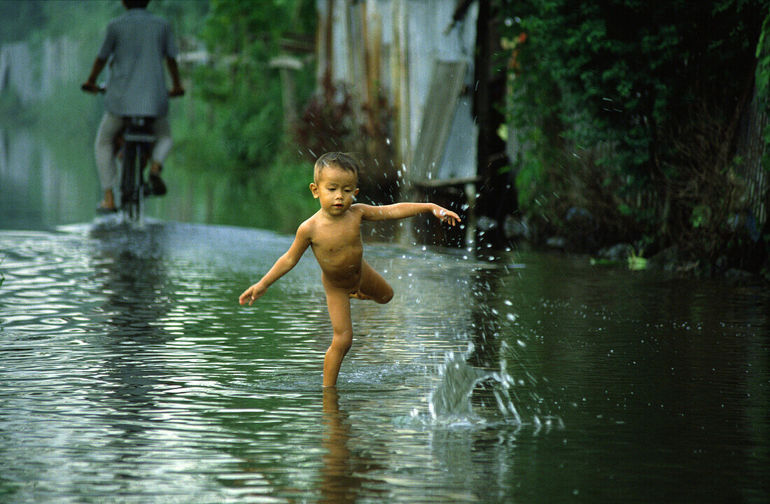 Boy playing in water, Monsoon, Bangkok, Thailand, Asia