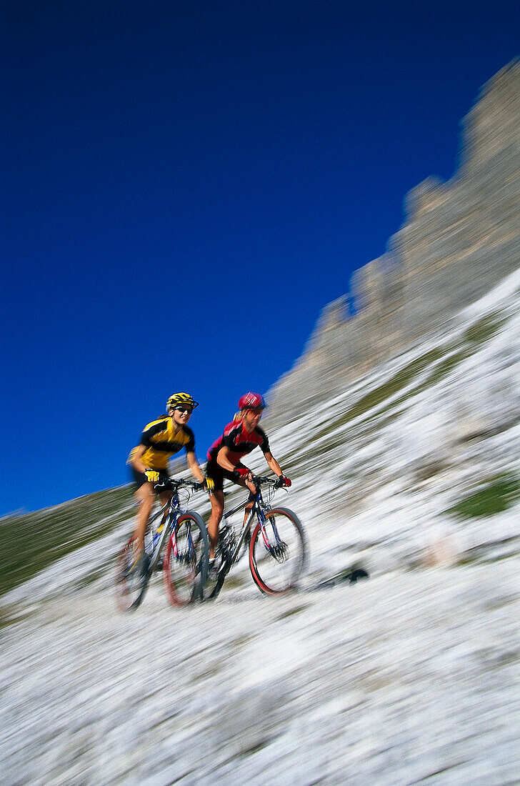 Couple on mountain bikes under blue sky, Cortina d'Ampezzo, Dolomites, Italy, Europe
