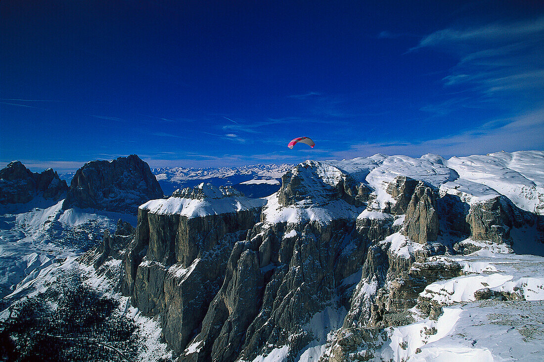 Parasail in flight above snow- covered mountains, Sella Ronda, Dolomites, Italy