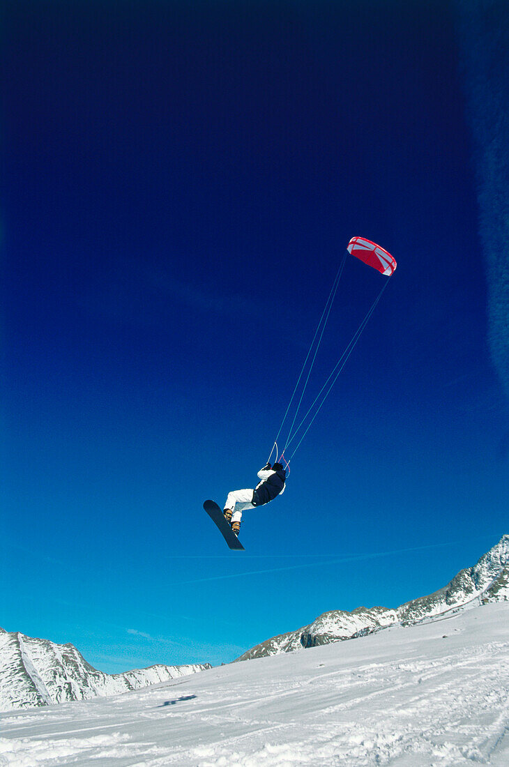 Mann springt beim Snowkiting, Lermoos, Lechtaler Alpen, Tirol, Österreich