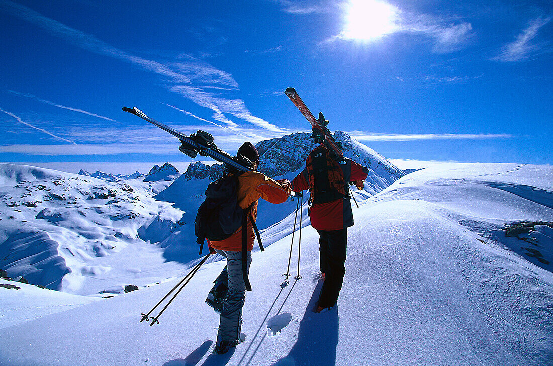 Zwei Personen mit Skiern in verschneiter Landschaft, Vorarlberg, Österreich, Europa