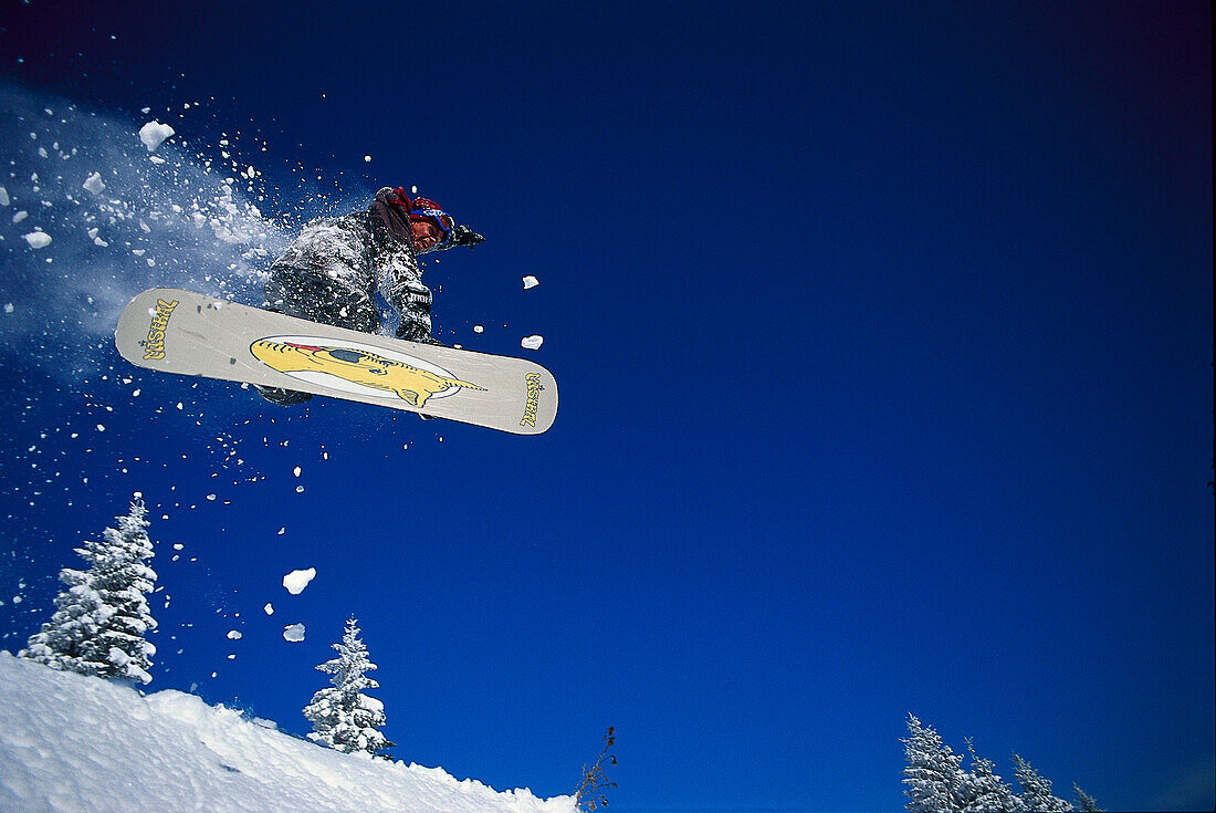 Snowboarder during jump under blue sky, Vorarlberg, Austria, Europe