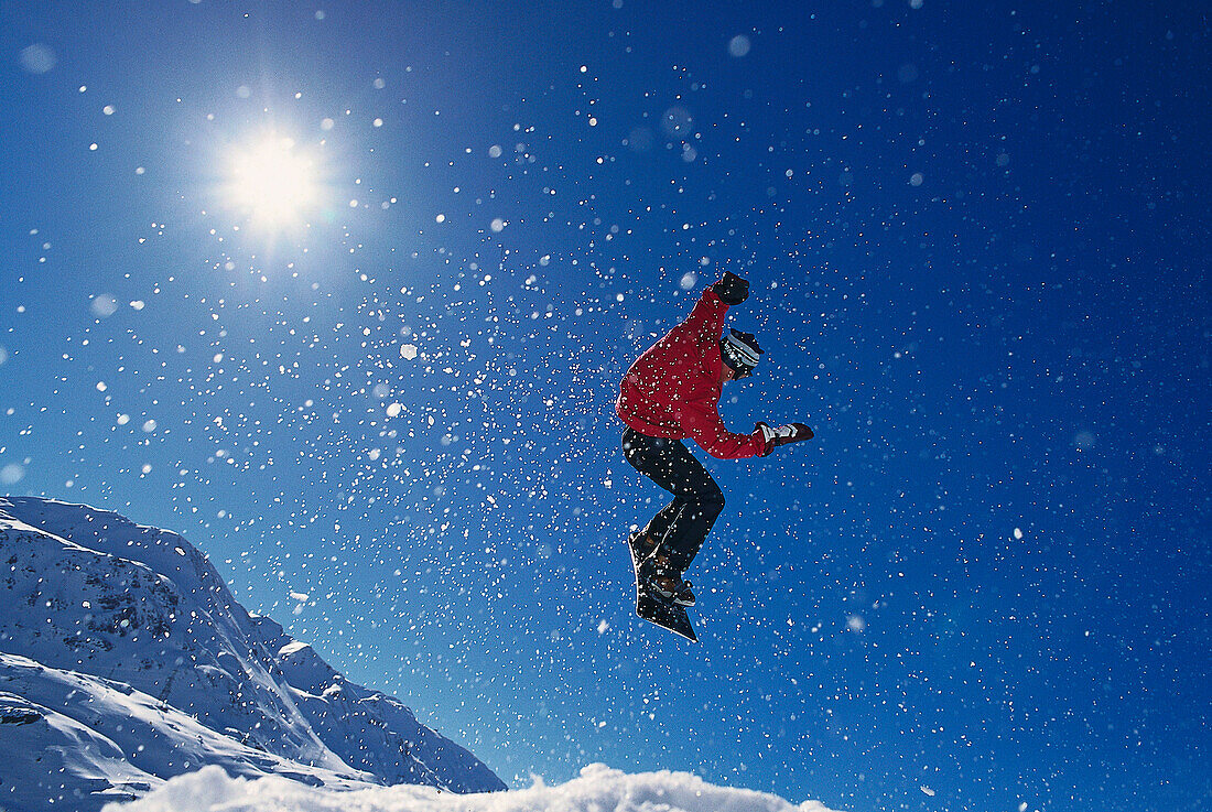 Snowboarder im Sprung vor blauem Himmel, Valuga, St. Anton, Tirol, Österreich