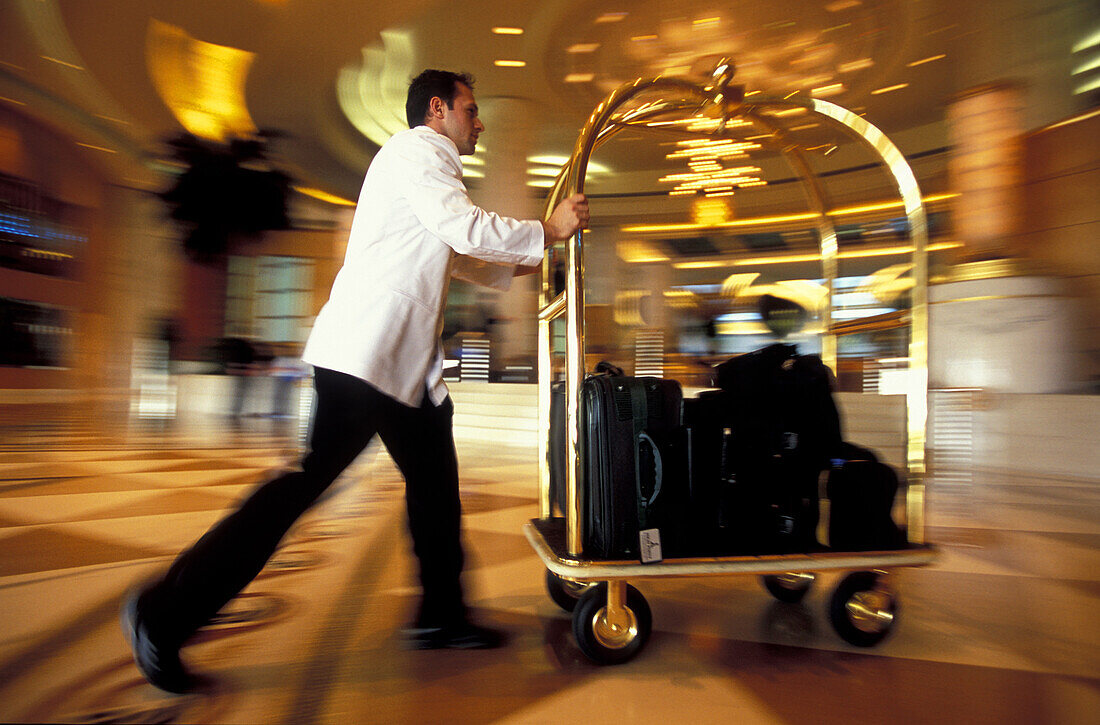 Employee pushing luggage through hotel's entrance hall, Dubai, United Arab Emirates, Middle East, Asia
