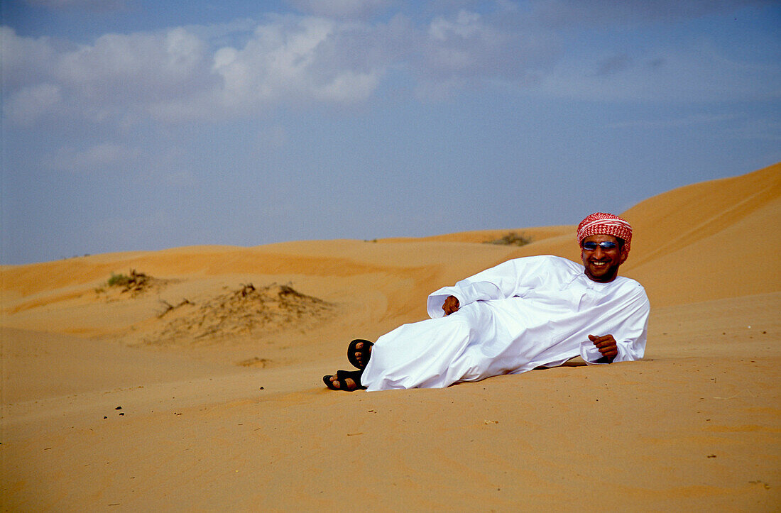 Mann liegt im Sand in der Wüste, Sultanat Oman, Vorderasien, Asien