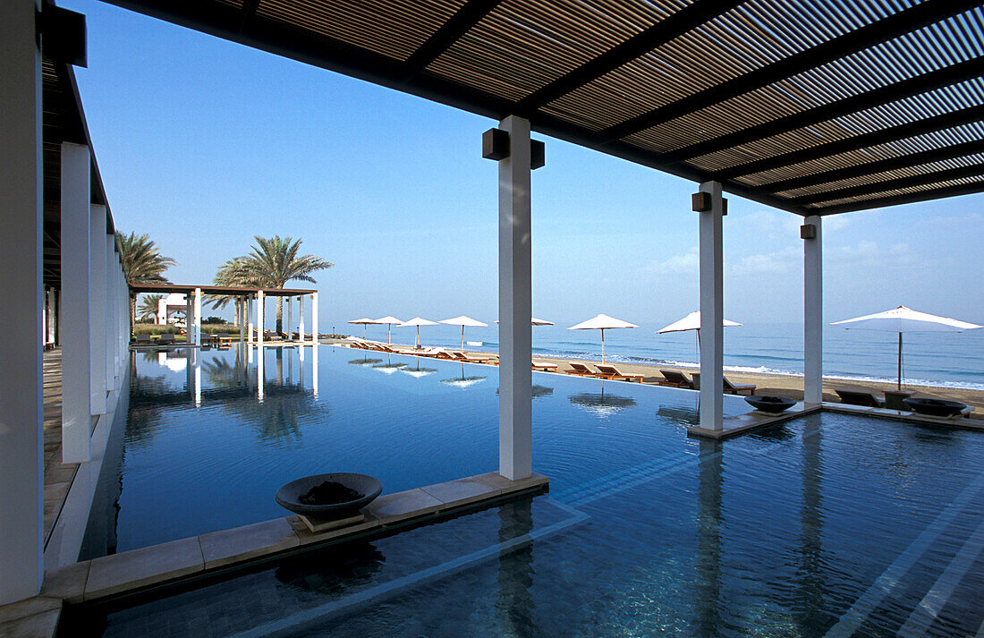 Sonnenschirme spiegeln sich im Pool, The Chedi Hotel, Maskat, Oman