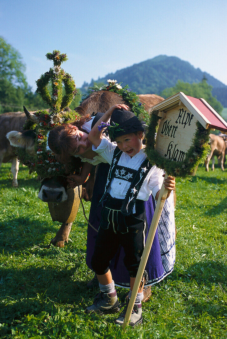 Frau und Junge in Tracht, geschmückte Kuh beim Almabtrieb, Oberstaufen, Allgäu, Deutschland