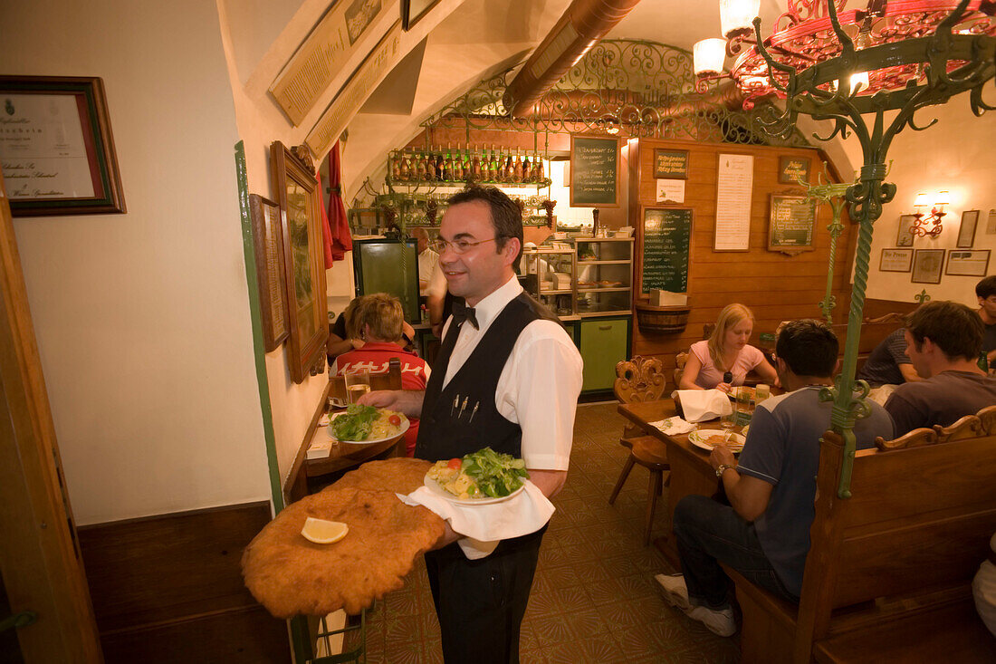 Waiter serving giant Wiener Schnitzel at Restaurant Figlmueller, Vienna, Austria