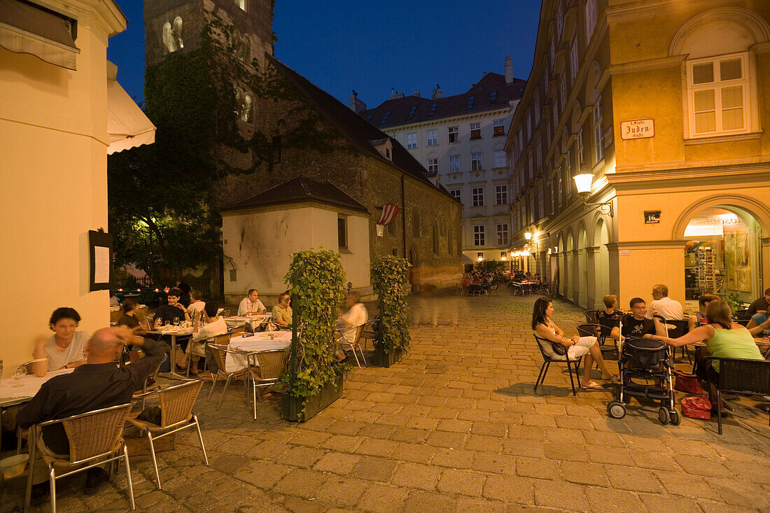 People sitting in the open-air area of the different restaurants in the Bermuda Triangle in the near of Ruprechtskirche in the evening, Vienna, Austria