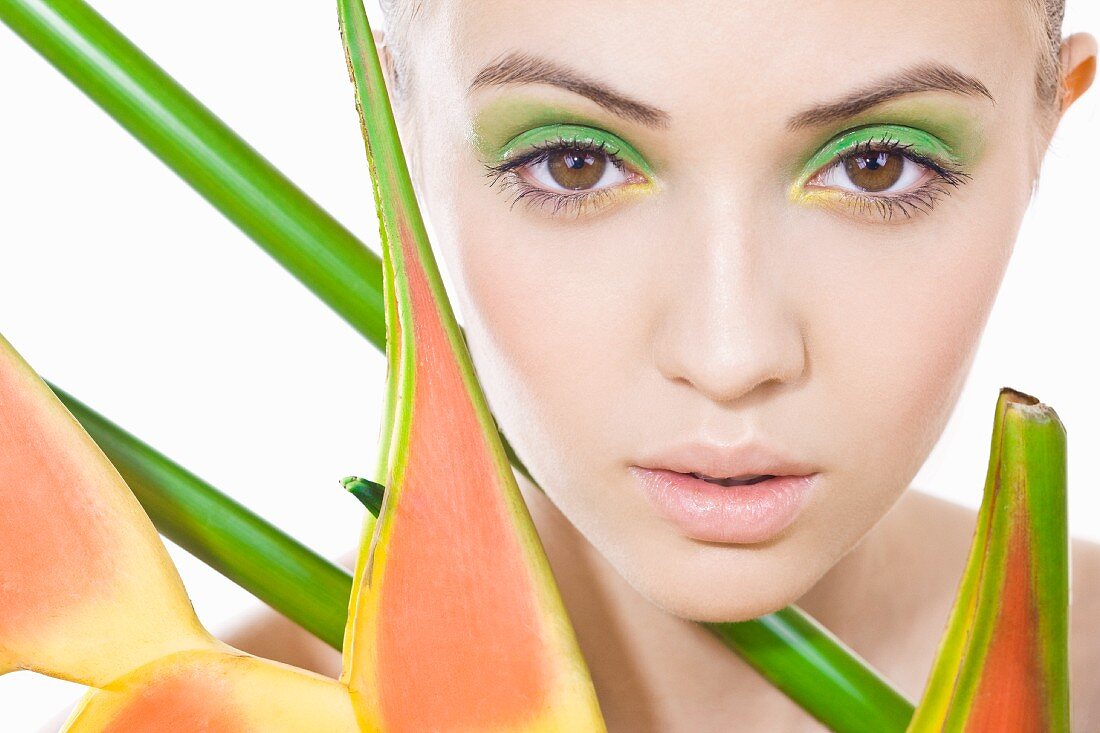 Junge Frau mit grünem Make-up und Pflanze