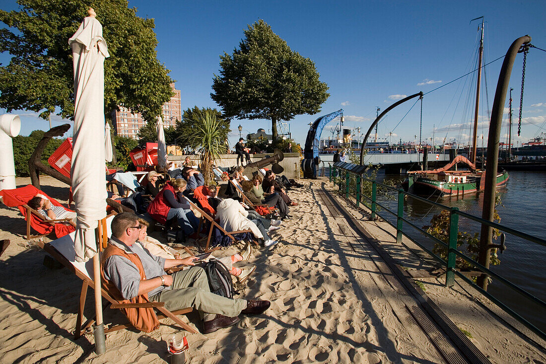 People sitting in deck chairs at harbour, People sitting in deck chairs at sandy open-air area of restaurant at Oevelgönne, Hamburg, Germany
