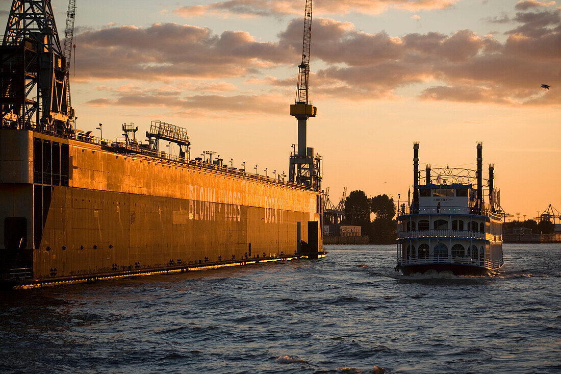 Paddlesteamer passing Bloom and Voss dockyard, Paddlesteamer passing a swimming dock of the Bloom & Voss Werft dockyard, in the dusk, Hamburg, Germany