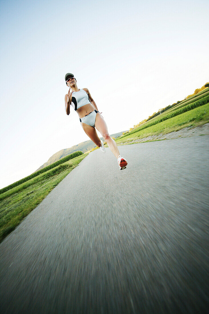 Junge Frau joggt auf Landstrasse