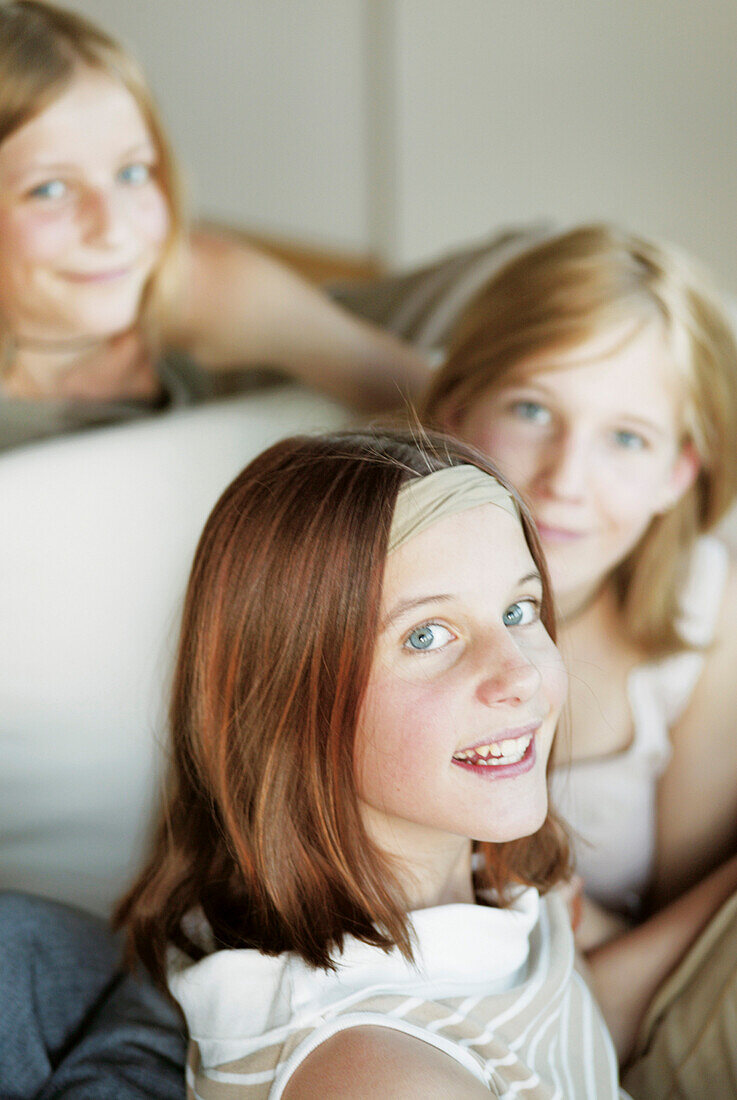 Drei weibliche Teenager sitzen auf einem Sofa