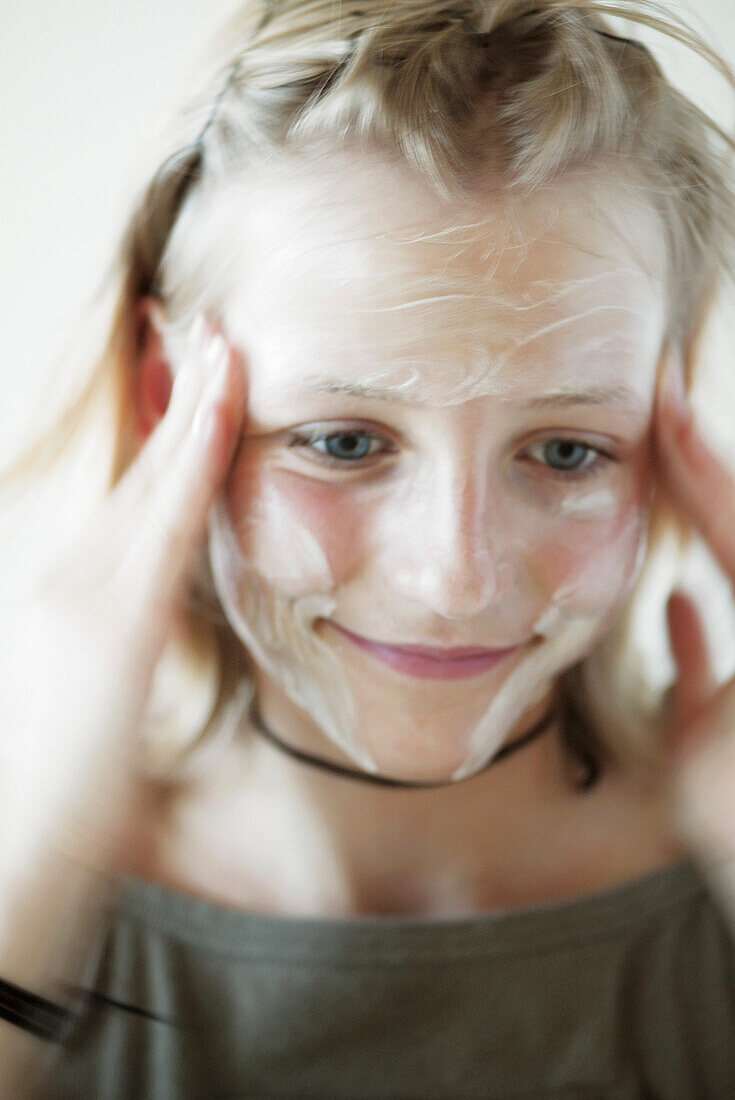 Teenage girl rubbing cream into face