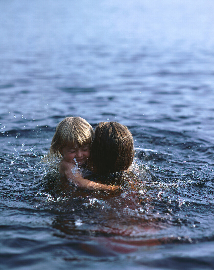 Mother holding little daughter, swimming
