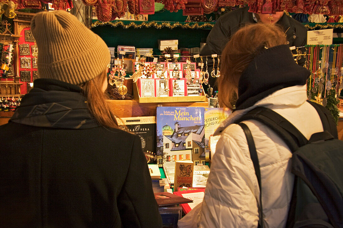 Two girls looking to market stall, Christmas market on Marienplatz, Munich, Bavaria, Germany