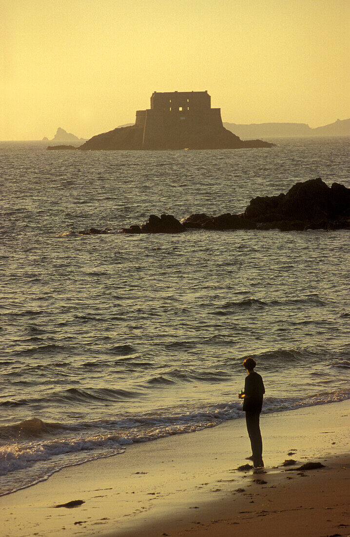 Person on beach at sunset, St. Malo, Brittany, France