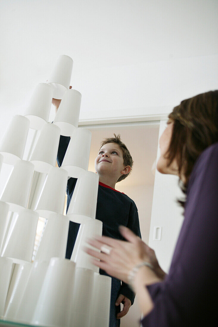 Junge baut einen Turm aus Plastikbechern